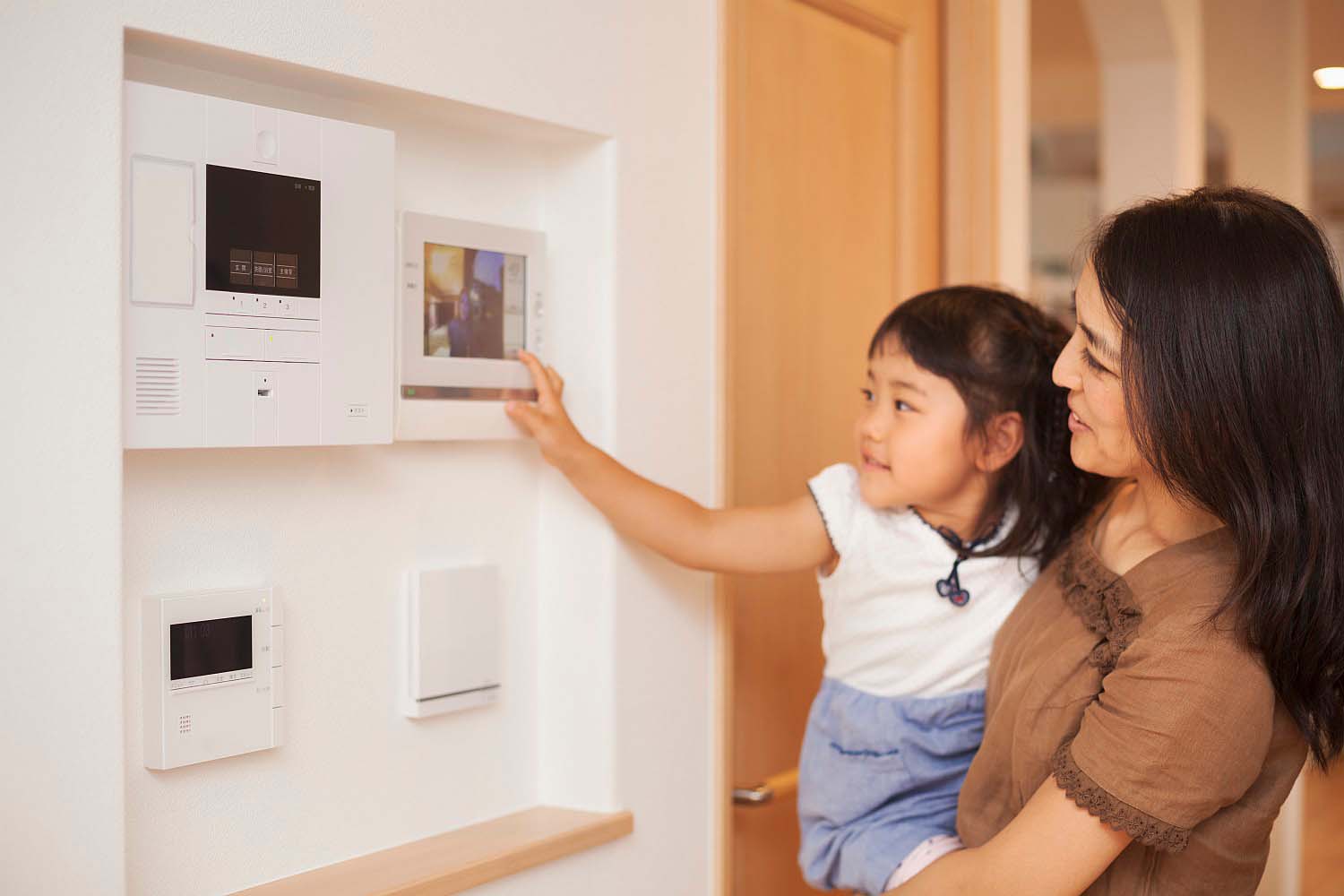 casa familiar mujer su hija mirando pantalla controles pared telefono entrada o entrada spain